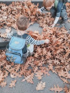 Kinder spielen im Herbst mit Blättern