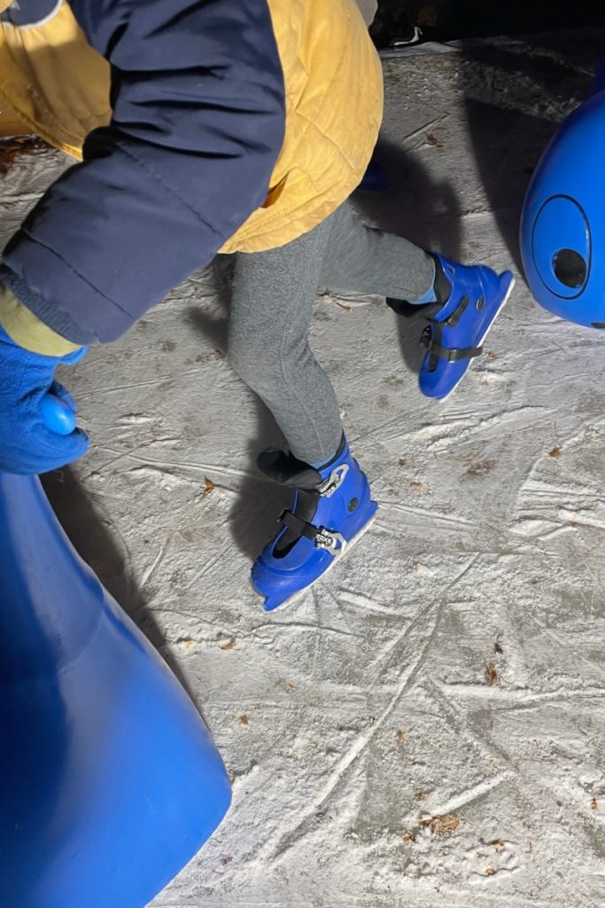 Kinderfüße in Schlittschuhen auf dem Eis