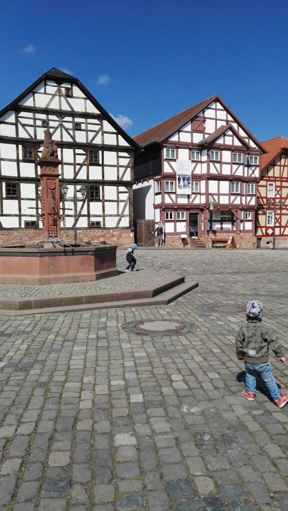 Zwei Kleinkinder auf dem Marktplatz mit Fachwerkhäusern im Freilichtmuseum Hessenpark
